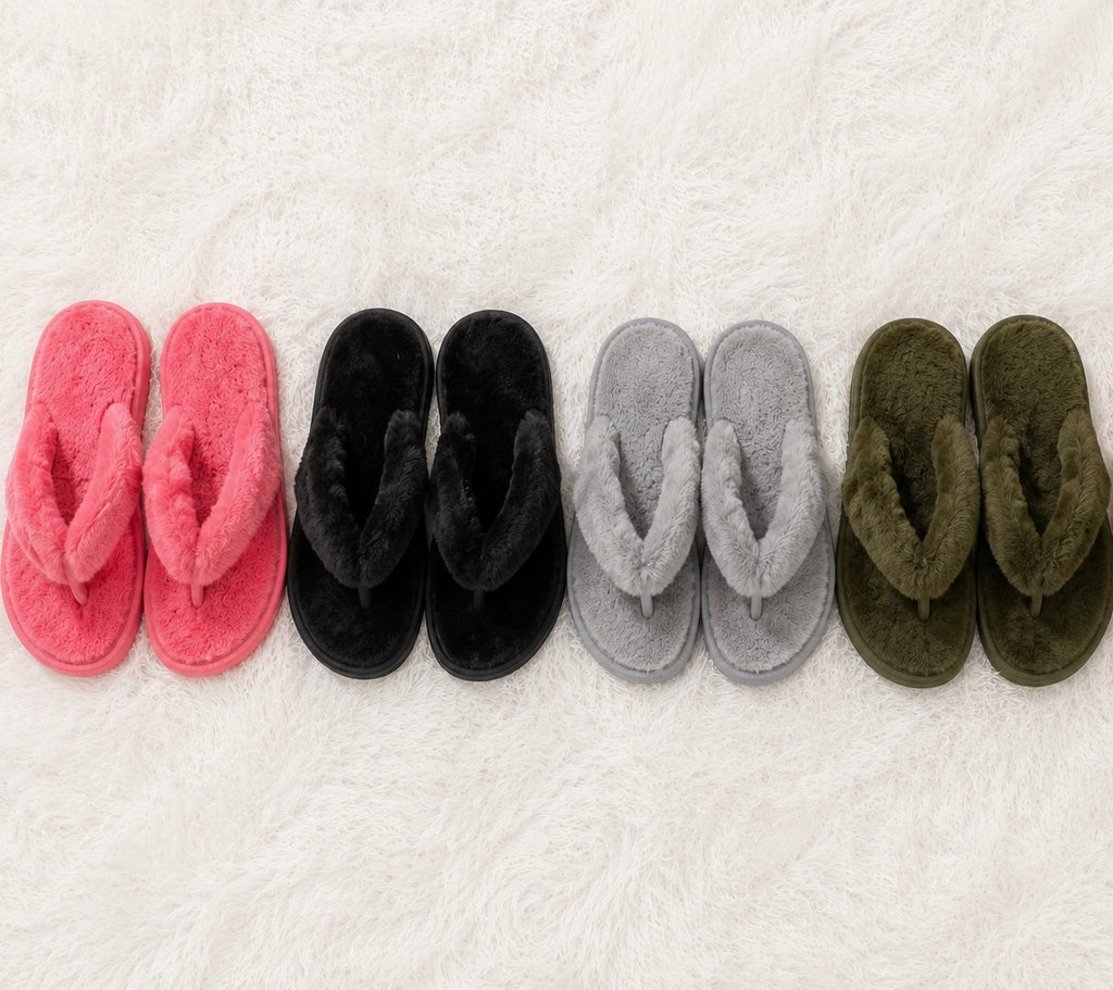Set of pink, black, gray, and green slippers arranged in a row on a white textured surface.