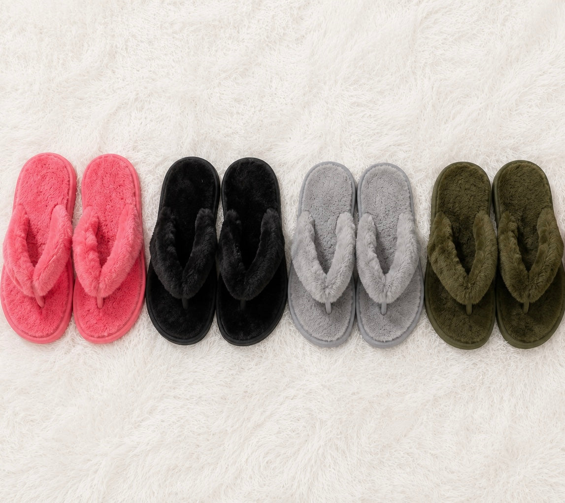 Set of pink, black, gray, and green slippers arranged in a row on a white textured surface.