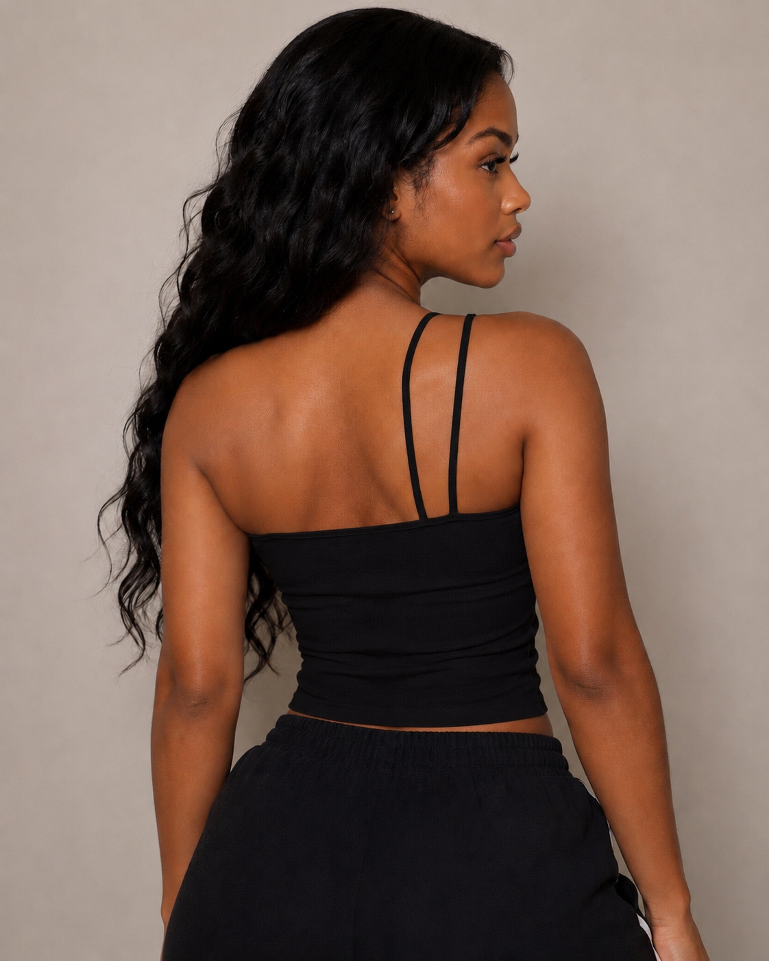 Woman wearing a black strappy top against a neutral background