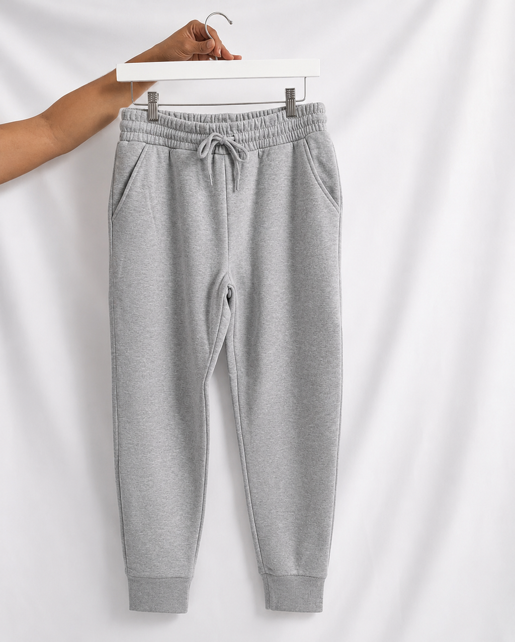 Gray sweatpants on a hanger against a white background