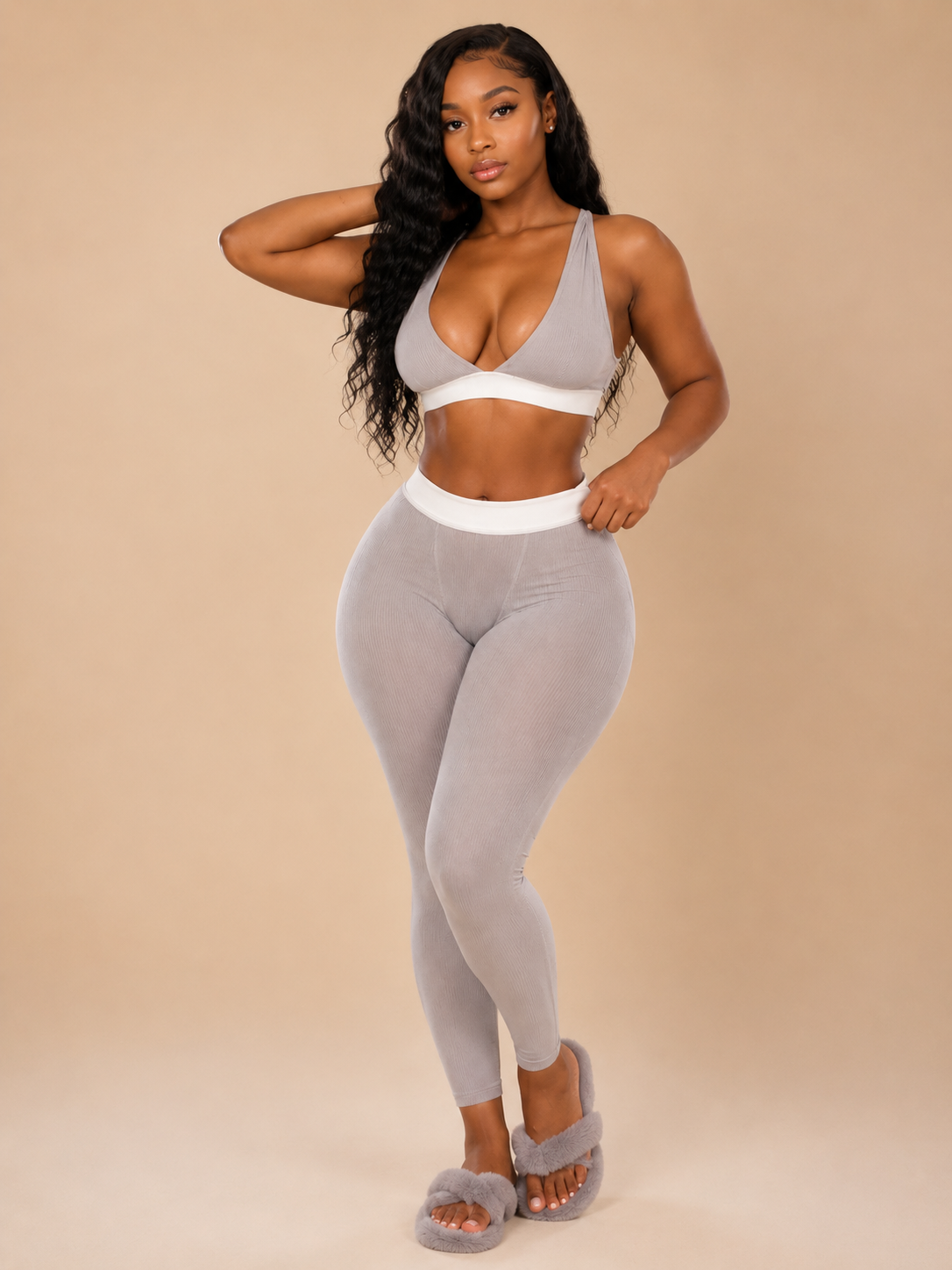 Woman wearing a gray sports bra and leggings set on a beige background