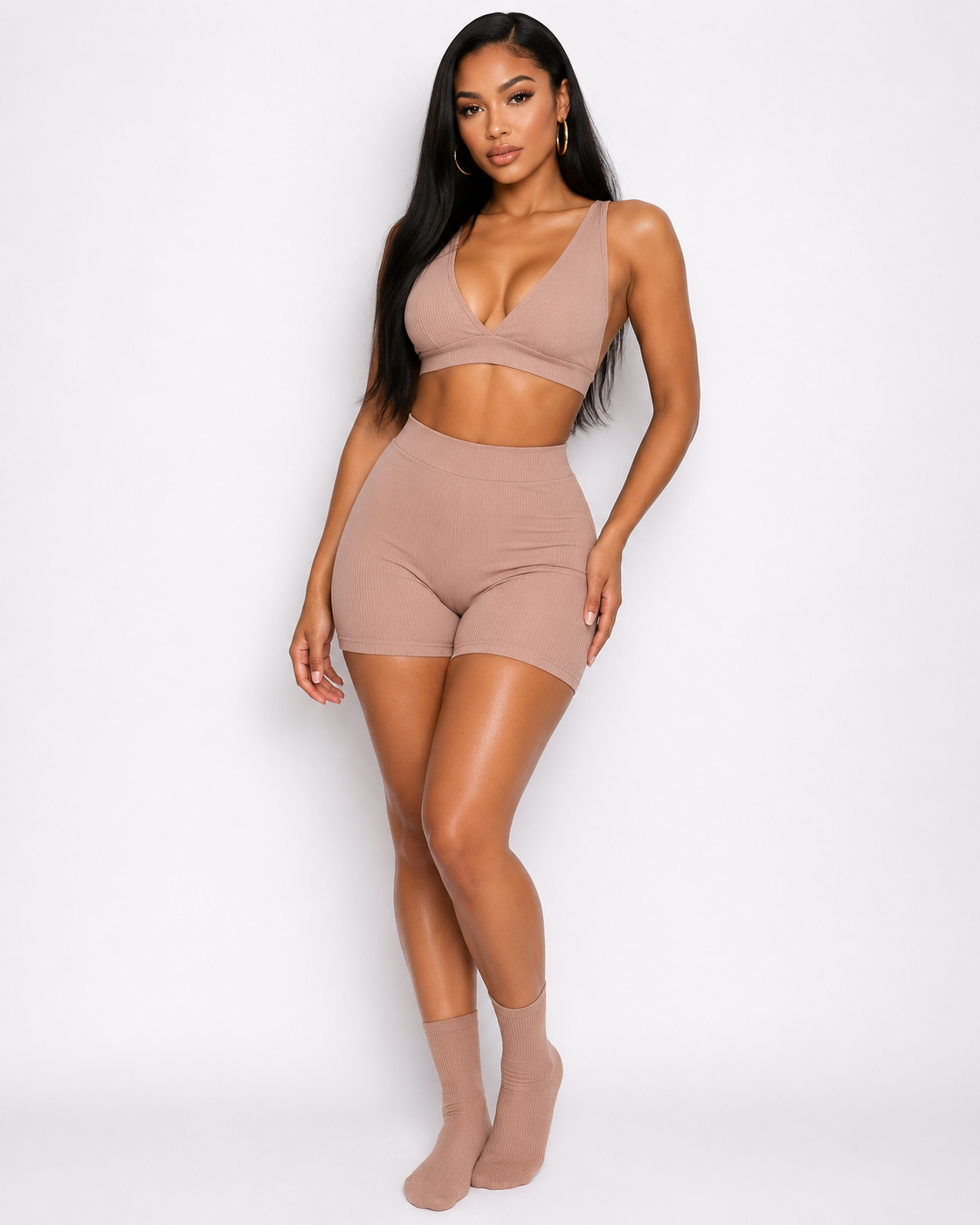 Woman wearing a beige sports bra and shorts set on a white background