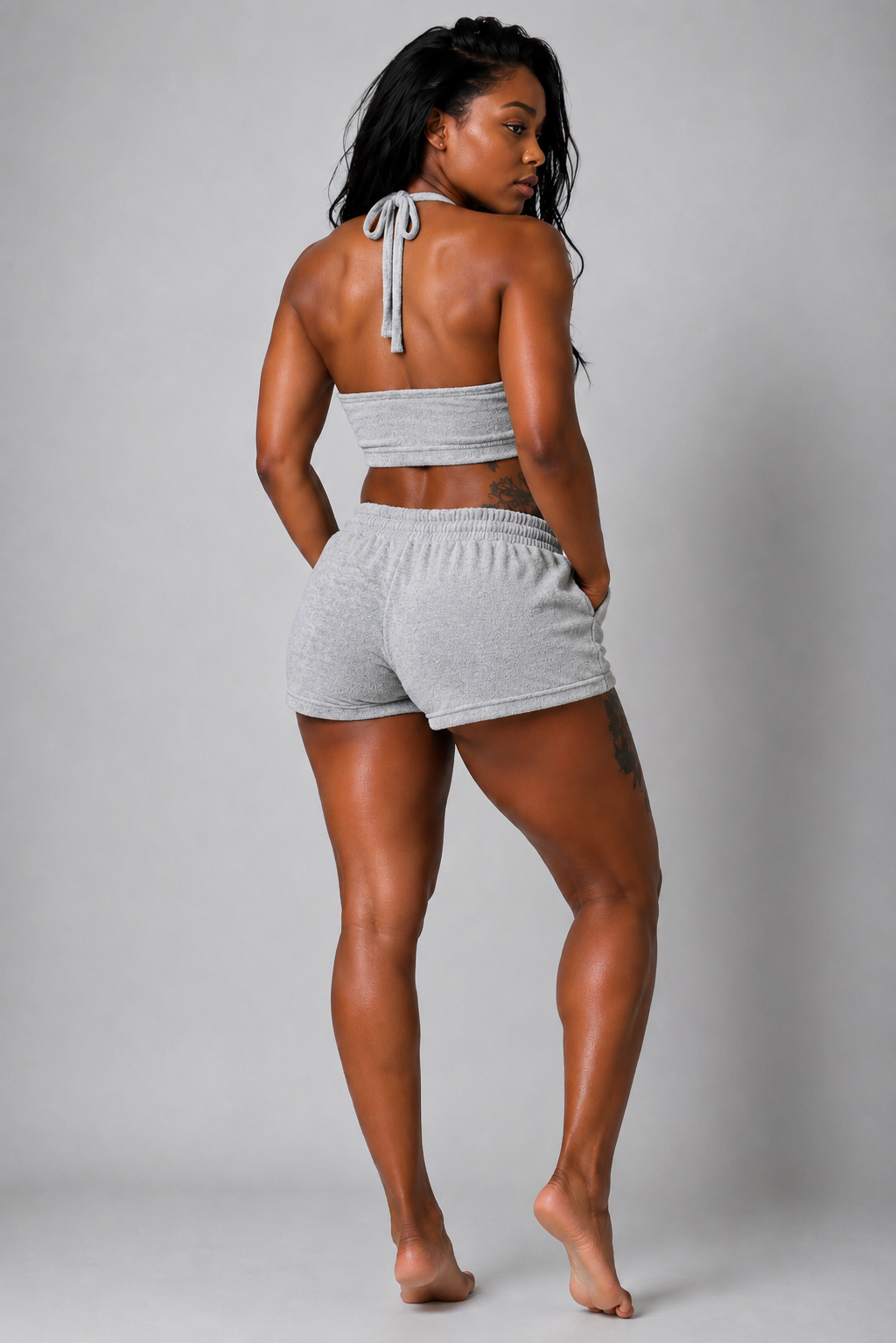 Woman wearing a gray tank top and shorts on a plain background